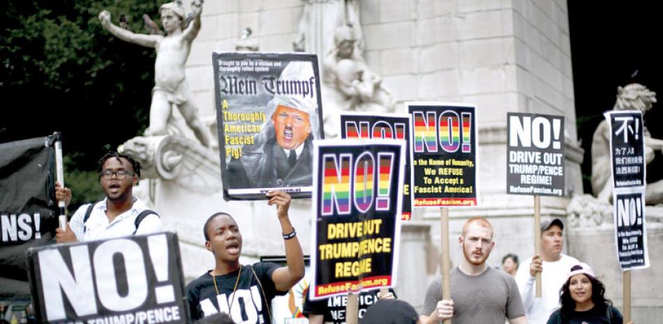 Promesas. Un pequeño grupo de personas se reúnen con carteles para protestar contra la decisión del Tribunal Supremo de restablecer una parte de la orden ejecutiva del presidente Trump.