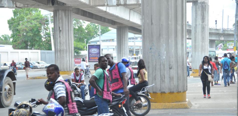 Un desafío. Están en todas partes e incursionan en cualquier oficio. Ignoran leyes y reglamentos de tránsito, bloquean calles y avenidas, trastornan el movimiento de peatones y se constituyen en un desafío grave a la autoridad. En esta imagen se observa a un tropel de motoconchistas haitianos debajo de un elevado, parte del torrente de inmigrantes que ingresan al territorio sin obstáculos, a través de la frontera.