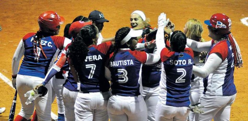 Geraldina Feliz, de República Dominicana, es felicitada por sus compañeras tras haber conectado un jonrón de tres carreras en el primer episodio del juego contra Aruba.