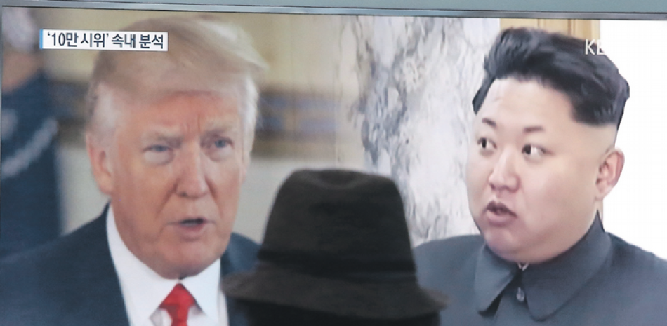 Rostros. Un hombre observa en televisión las imágenes del presidente de EEUU, Donald Trump, y del líder de Corea del Norte, Kim Jong Un.