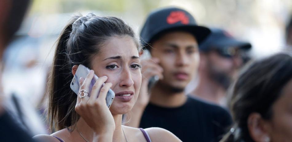 Unas personas, conmocionadas, hablan por teléfono en una calle de Barcelona, España, después de que una camioneta atropellara a varias personas en la concurrida zona de Las Ramblas, el jueves 17 de agosto de 2017. (AP Foto/Manu Fernandez)