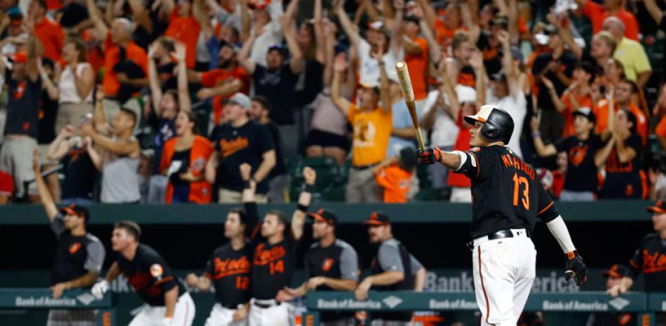 Manny Machado observa con el bate en la mano la trayectoria de la pelota mientars el publíco en Baltimore festeja su su gran batazo.