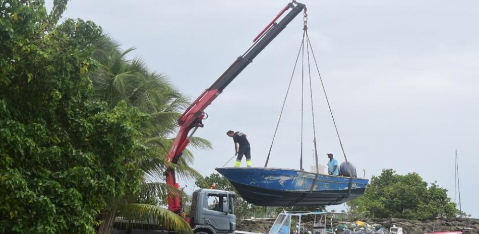 Varios hombres sacan botes del agua antes de la llegada del huracán María, en la zona de Galbas, en Santa Ana, en la isla caribeña francesa de Guadalupe, el lunes 18 de septiembre de 2017. (AP Foto/Dominique Chomereau-Lamotte)