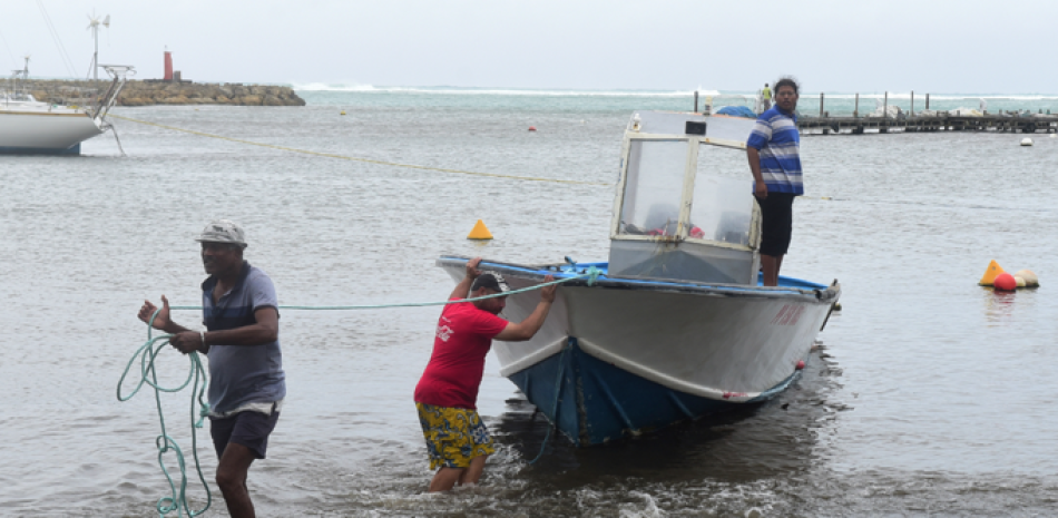 Unos hombres sacan un bote del agua antes de que llegue el huracán María, en Sainte-Anne, isla de Guadalupe, el lunes 18 de septiembre de 2017. (AP Photo/Dominique Chomereau-Lamotte).