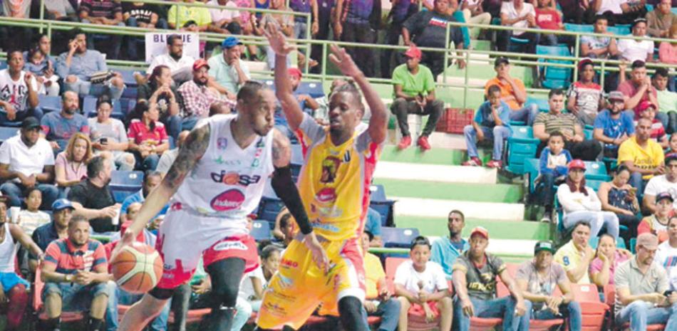 Trey Gilder, del Dosa, maneja el balón ante la defensa de Juan Miguel Suero, del Enriquillo, durante el partido del miércoles en la serie final del torneo de baloncesto superior de La Vega.