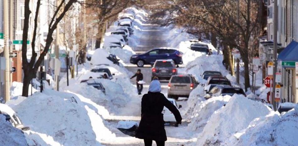 Trabajo. Mollie Lane carga una pala llena de nieve mientras limpia el frente de su casa en South Boston, un vecindario en Boston, ayer. La temperatura sigue baja, en menos 30 grados, y la gente ya empieza a recuperarse.