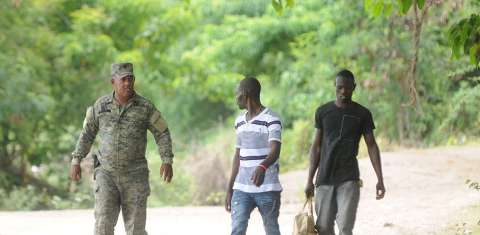 Un militar dominicano camina junto a dos haitianos indocumentados detectados cuando intentaron ingresar al territorio nacional.