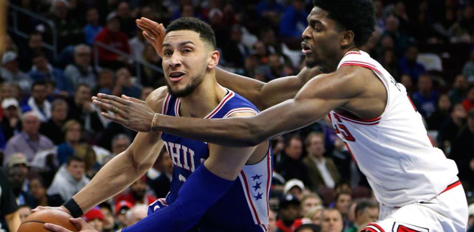 Ben Simmons, a la izquierda, de los Sixers, maneja el balón ante la defensa de Justin Holiday, de Chicago, en la segunda mitad del partido de anoche en el baloncesto de la NBA.