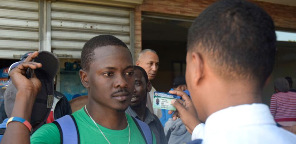 Un oficial de migración chequea el carné de identidad de un haitiano que intentaba ayer abordar un autobús para viajar a la ciudad de Santiago de los Caballeros.