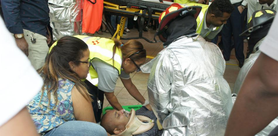 Asistencia. Personal paramédico y bomberos del Aeropuerto Las Américas mientras levantaban al francés que cayó del tercer nivel tras enredarse en la escalera.