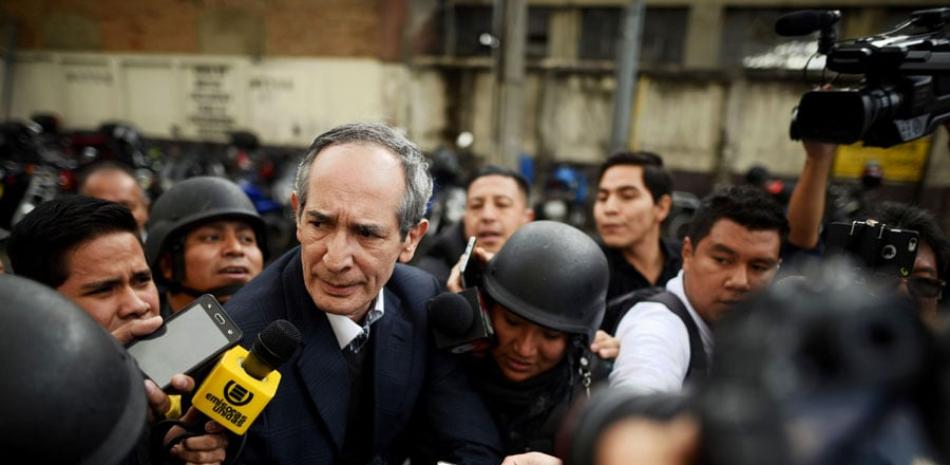 Esposado. El expresidente de Guatemala, Álvaro Colom, al centro, camina escoltado tras ser capturado ayer.