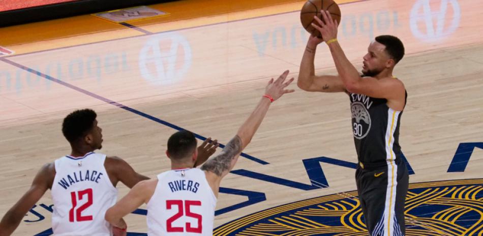 Stephen Curry, de Golden State Warriors, tira a la canasta ante la defensa de Tyrone Wallace y Austin Rivers, de los Clippers en el partido del jueves en el baloncesto de la NBA.