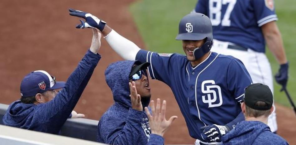 Fernando Tatis es saludado por varios compañeros al llegar al dogout luego de haber dado un hit.