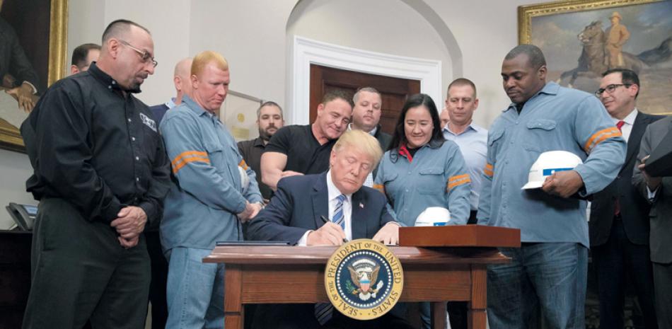 Casa Blanca. El presidente Donald J. Trump, firma el decreto presidencial junto a trabajadores del acero ayer, en el Salón Roosevelt.