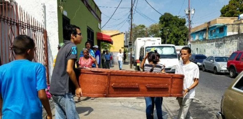 Un grupo de personas carga con el ataúd de una víctima que murió en el incendio del centro de reclusión de la Policía Estadal de Carabobo  en Valencia (Venezuela.