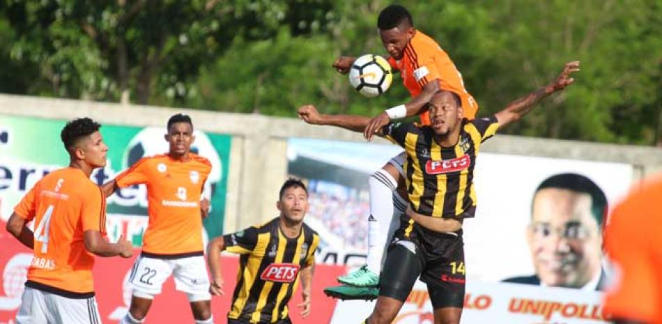 Domingo Peralta, de Moca, delante, trata de cabecear el balón cuando tiene encima a un jugador de Cibao.