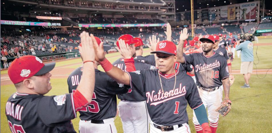 Wilmer Difo y Howie Kendrick festejan con varios de sus compañeros luego que los Nacionales se anotaron el triunfo anoche.