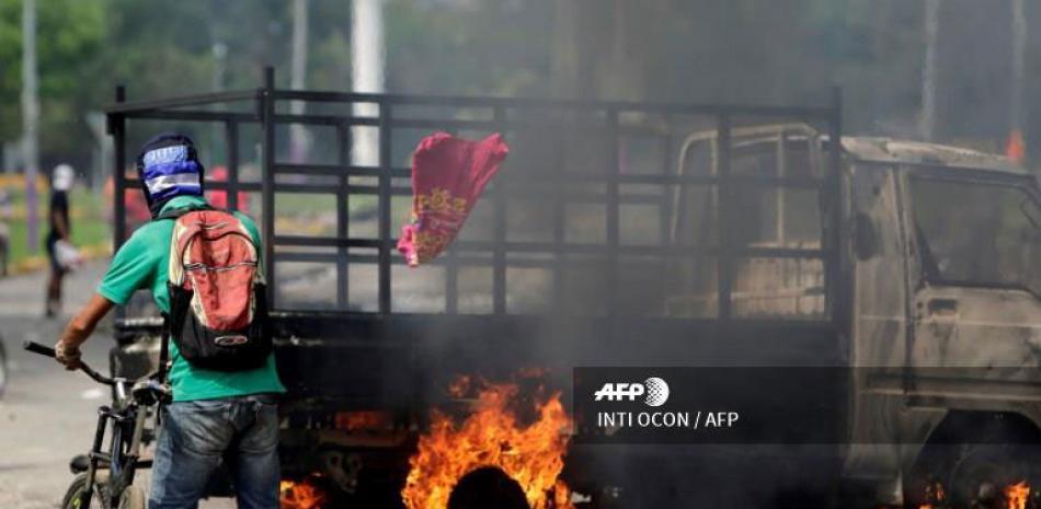 Fuego. Un hombre pasa cerca de un vehículo incendiado, durante las protestas en Masaya, a unos 40 kilómetros al sureste de managua, ayer.