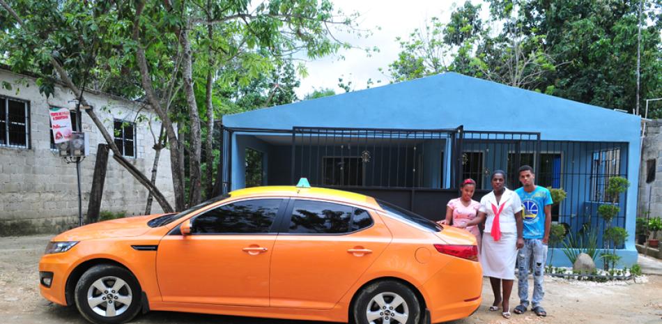 Cambio. Albania Hernández, "La Sierva del 12", y sus dos hijos, mostrando su nuevo vehículo y su casa remodelada.