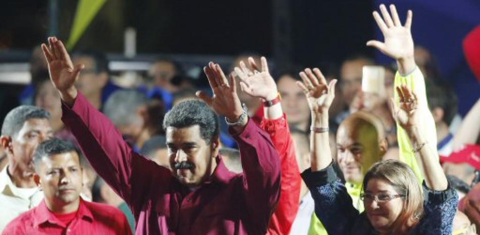 El presidente venezolano, Nicolás Maduro, y su esposa, Cilia Flores, saludan a sus partidarios en el palacio presidencial de Caracas, Venezuela. (AP Foto/Ariana Cubillos)