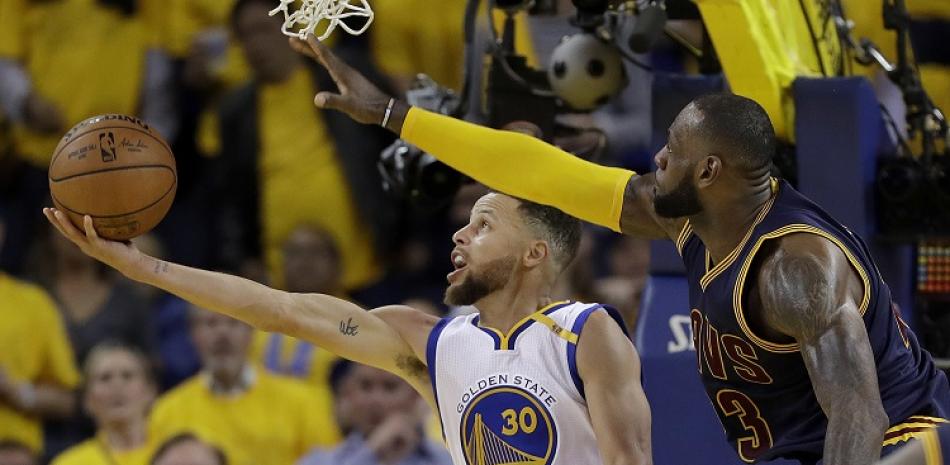 LeBron James, de Cleveland, trata de evitar un canasto de Stephen Curry, de Golden State, en acción de uno de los partidos de la serie final del año pasado.