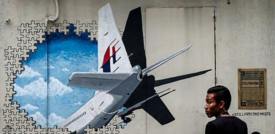 Un joven pasa por delante de una pintura mural del avión MH370 de Malaysia Airlines, en Kuala Lumpur. El plazo fijado por el Gobierno de Malasia para la segunda búsqueda del avión de Malaysia Airlines, desaparecido en 2014 con 239 personas a bordo, concluye este martes 29 de mayo tras revisar más de 80,000 kilómetros cuadrados y sin rastro del aparato. EFE/ Fazry Ismail.