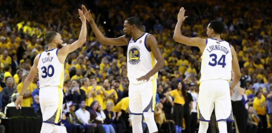 Stephen Curry, Kevin Durant y Sean Livington se felicitan luego que los Warriors construyeron una ventaja que no perdieron jamas en el primer partido de la final de la NBA.