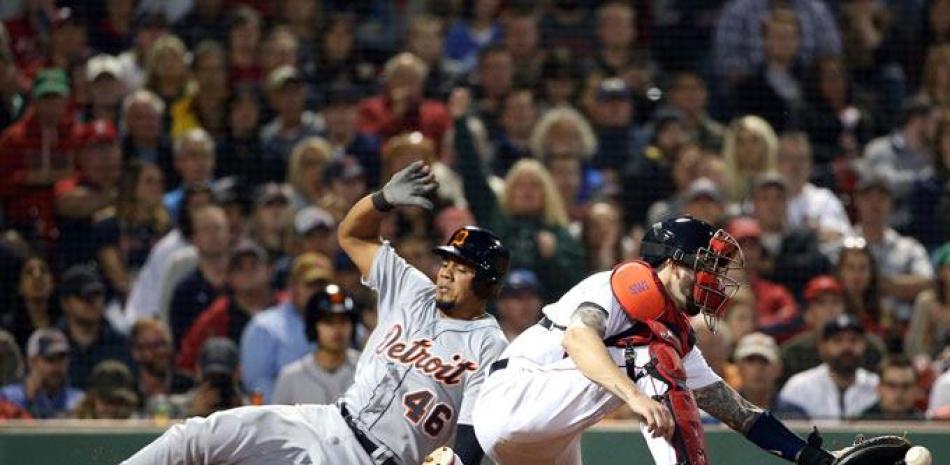 Jeimer Candelario, de Detroit, se desliza a salvo en el plato para anotar tras un sencillo de José Iglesias mientras el receptor de los Medias Rojas, Blake Swihart atrapa la pelota en el octavo inning del partido de ayer.