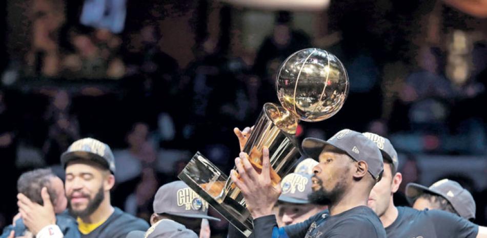 Kevin Durant, junto a algunos de sus compañeros, sostiene el trofeo de campeón conquistado por los Warriors, equipo que anoche culminó la barrida ante los Cavaliers, el partido terminó con marcador 108-85.