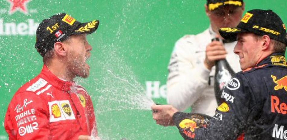 Sebastian vettel recibe un baño de champagne de Max Verstappen, quien ocupó el tercer lugar en la carrera de Fórmula Uno efectuada este domingo.