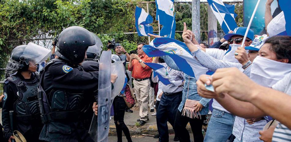 Marcha. Manifestantes gritan consignas frente a policías durante la marcha llamada “Marcha de las Banderas” en contra el gobierno del presidente Daniel Ortega, ayer en Managua.