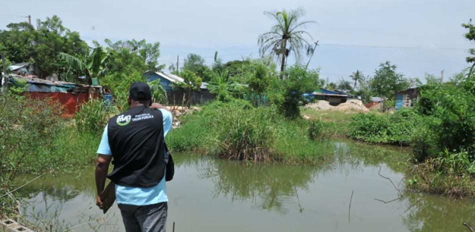 Casos. Un inspector del Ministerio de Salud Pública señala un espacio de maleza y agua contaminada cerca de viviendas en SDO.