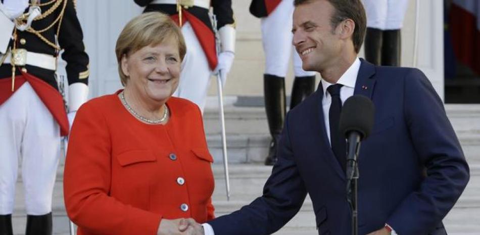 a canciller alemana, Angela Merkel, se da la mano con el presidente francés, Emmanuel Macron, en Marsella (Claude Paris / AP)