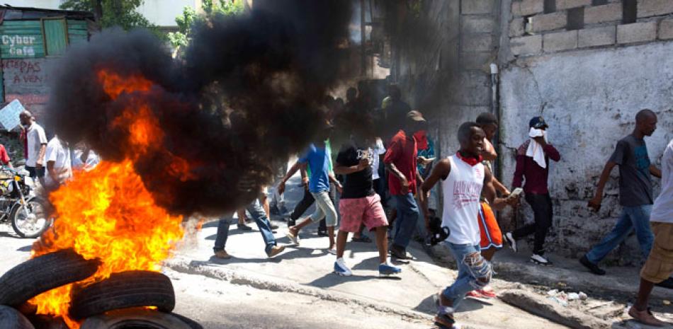Reclamo. Manifestantes caminan junto a neumáticos quemándose durante una protesta exigiendo saber cómo los fondos de Petrocaribe han sido utilizados por las administraciones actuales y pasadas, en Haití.