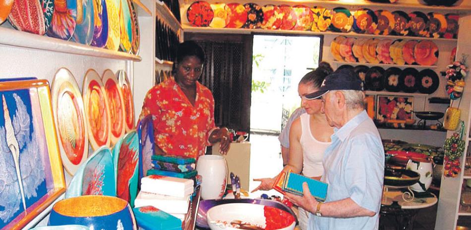 Artista. Durante su estadía en República Dominicana, Charles Aznavour tuvo la oportunidad de conocer de la artesanía, la pintura, la gastronomía y la música dominicana. Según Roberto Cavada, le encantó la parte del país que conoció y los colores del Caribe. En la imagen, cuando visitaba el taller de Bibi León, en La Romana.