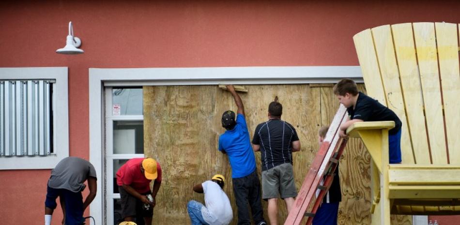 Trabajadores refuerzan las ventanas de un establecimiento local ante la llegada del huracán Michael a Florida.
