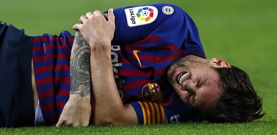 El delantero argentino Lionel Messi da muestras de dolor tras lesionarse durante el partido de este sábado en la liga española contra el Sevilla.