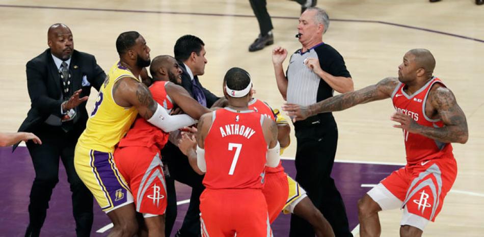 Pelea. LeBron James, de los Lakers, sostiene a Chris Paul, de los Rockets, quien intercambia golpes con Rajon Rondo (oculto) en el partido del sábado por la noche en el baloncesto de la NBA.