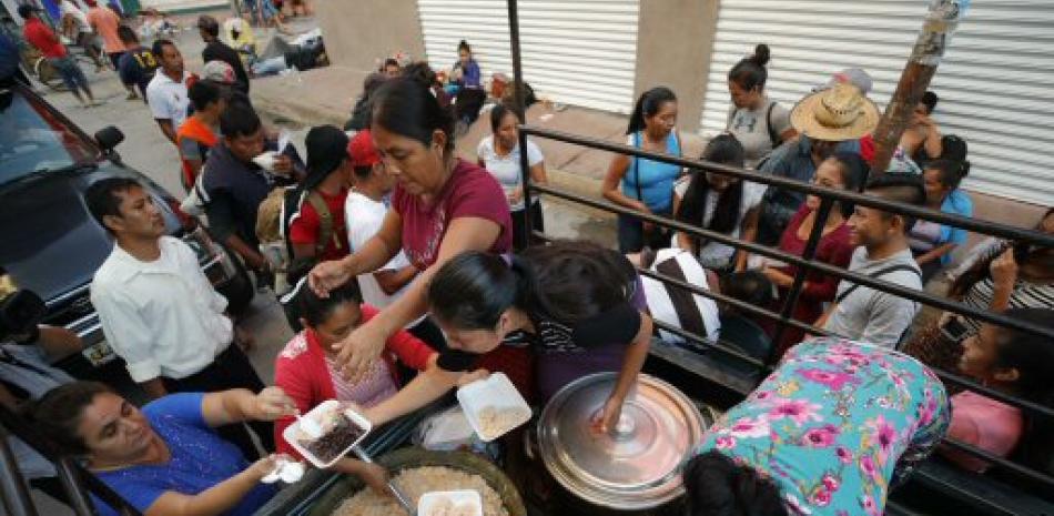 Migrantes hondureños reciben comida caliente preparada y distribuida por ciudadanos mexicanos durante su travesía hacia su objetivo, Estados Unidos.