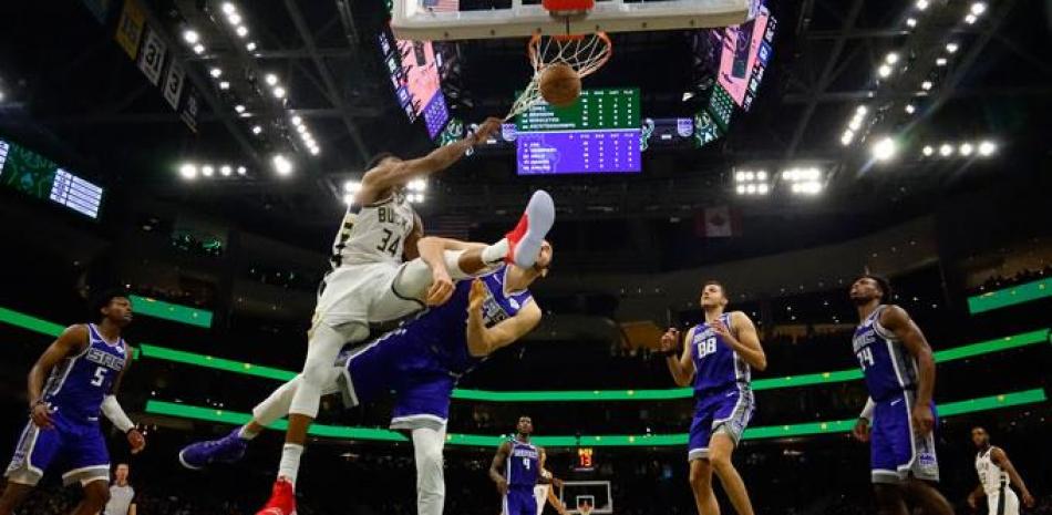 Giannis Antetokounmpo, de los Bucks, realiza un potente donqueo sobre Kosta Koufos, de Sacramento, en acción del encuentro de la NBA ayer.