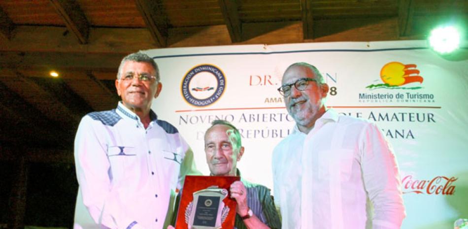 Rafael Villalona y Carlos Elmudesi, presidente y vice de la Fedogolf entregan una placa de reconocimiento al señor Carlos Lizarazo, por sus aportes al golf.