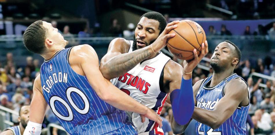 Andre Drummond trata de abrirse paso entre dos defensores de los Magic de Orlando en el partido que ganaron los Pistons.