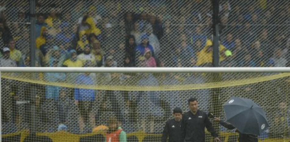Varios jugadores figuran en la cancha mojada minutos después de anunciarse la posposición del partido entre Boca y River