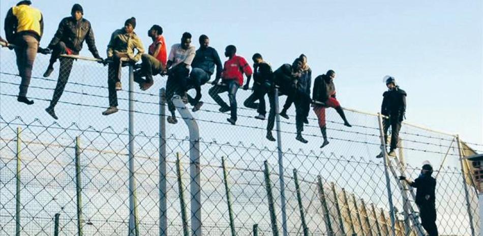 Ceuta, España. Policías españoles tratan de disuadir a inmigrantes encaramados a la valla de Melilla, fronteriza con Marruecos, el 22 de octubre del 2014.