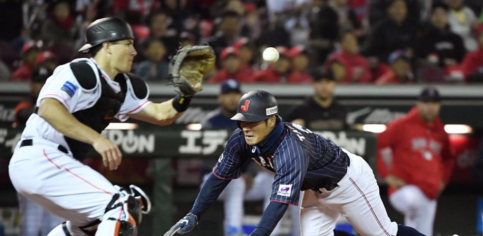 Ryosuke Kikuchi's, de Japón, se lanza de cabeza ante el intento del receptor de MLB J.T. Realmuto por hacerle out en el plato.