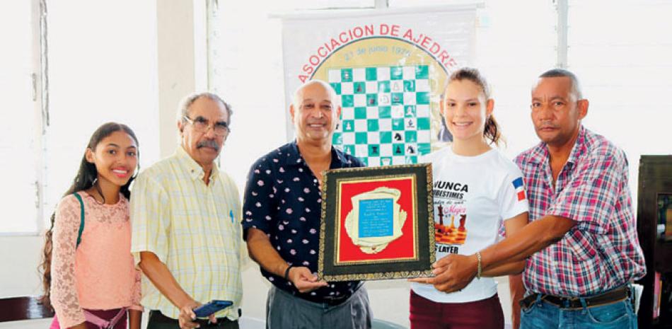 William Paulino, Enmanuel Trinidad, Carlos Lantigua y Jennifer Sánchez entregan una placa de reconocimiento a la campeona nacional de ajedrez juvenil femenino Raydily Rosario Almánzar.