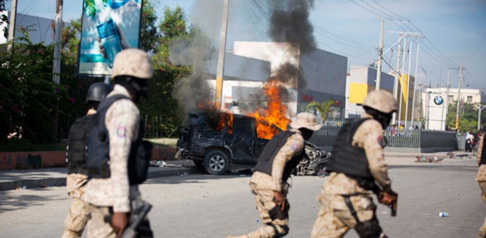 Atropellamiento. Militares pasan cerca de un carro que arde, luego de que atropellara y matara a seis personas en la capital, en medio de la tensión en la capital, luego de una violenta protesta el domingo pasado.