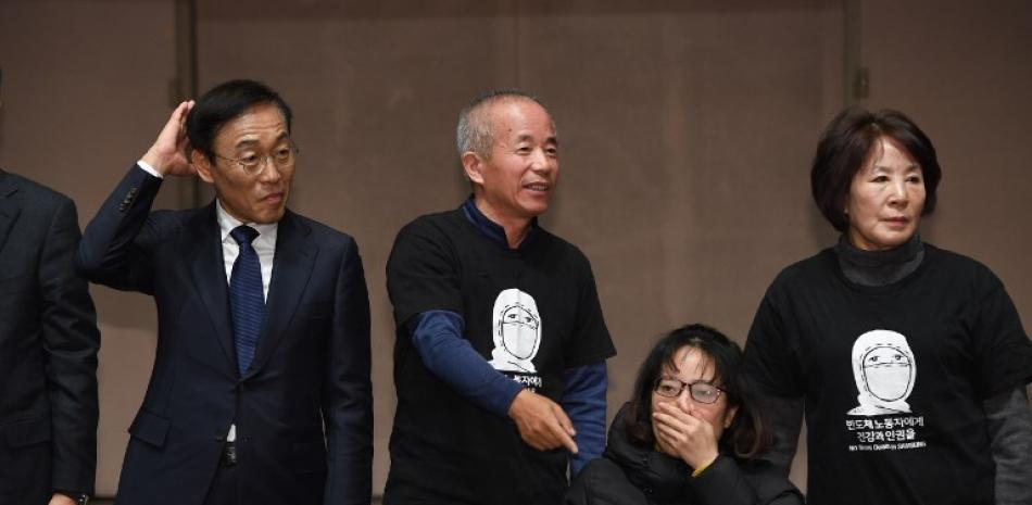 El copresidente de Samsung Electronics, Kim Ki-nam posa para una foto con familiares de las víctimas de a trabajadores que desarrollaron cáncer después de trabajar en sus fábricas de semiconductores y LCD.