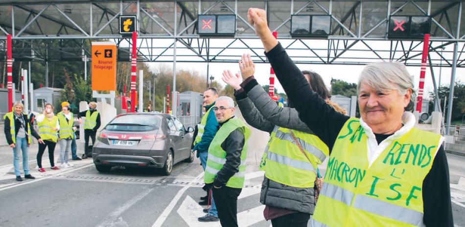Letrero. Un manifestante con su chaleco amarillo protesta con la insignia de que "Macron nos dio el impuesto de los ricos", ayer en Biarritz.