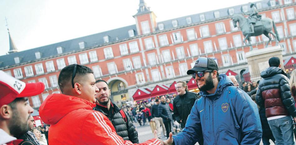 Hinchas de Boca Juniors y River Plate se estrechan la mano al encontrarse en la Plaza Mayor de Madrid, el viernes 7 de diciembre de 2018.